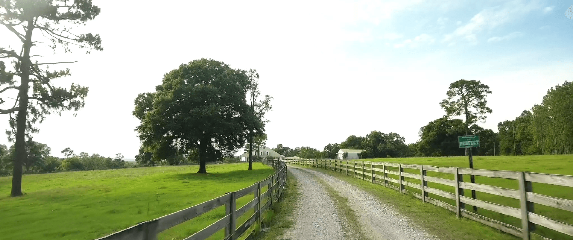 Farm entrance with gravel road and wooden fences
